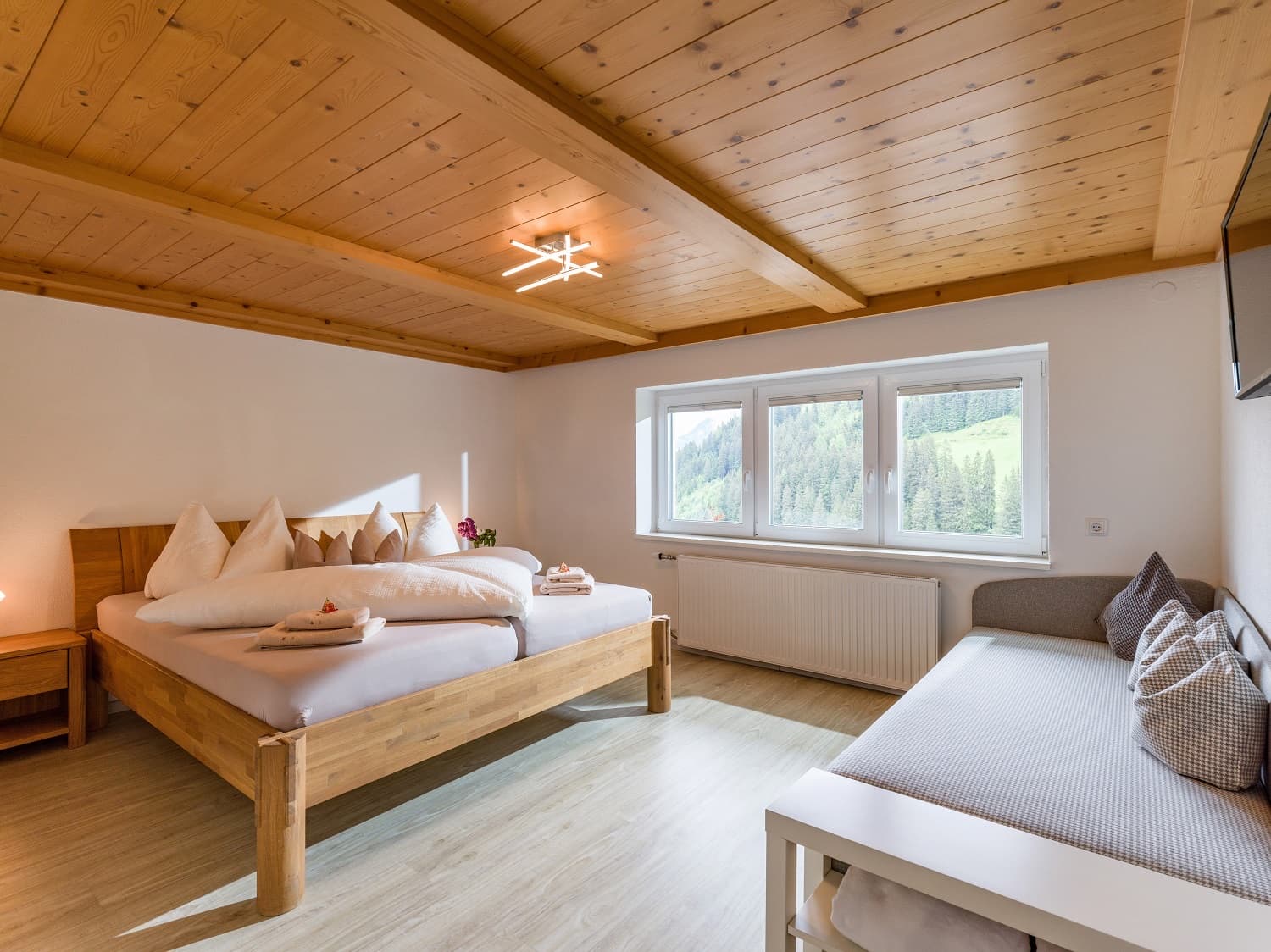 Schlafzimmer mit Doppelbett, Holzdecke und Schlafsofa
